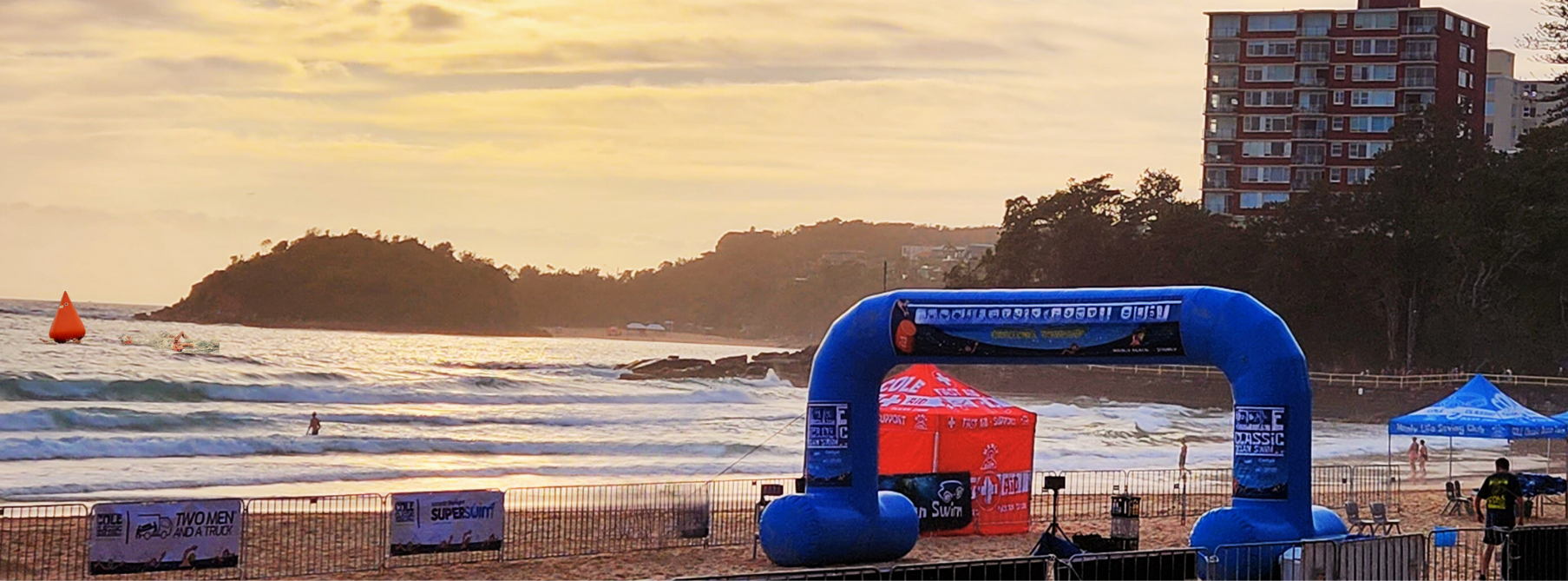 Conical orange marker buoys made by Fleximake for NSW Swimming Australia, shown in use during an open water championship with many swimmers racing past the buoys.